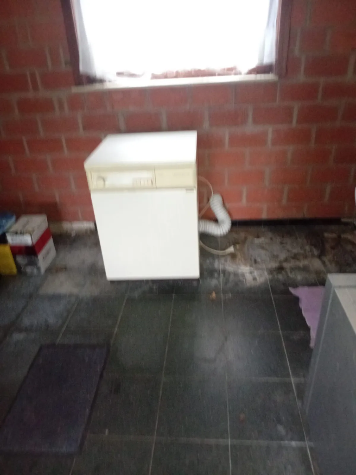 Berging met tegelvloer en een oud wit toestel onder het raam