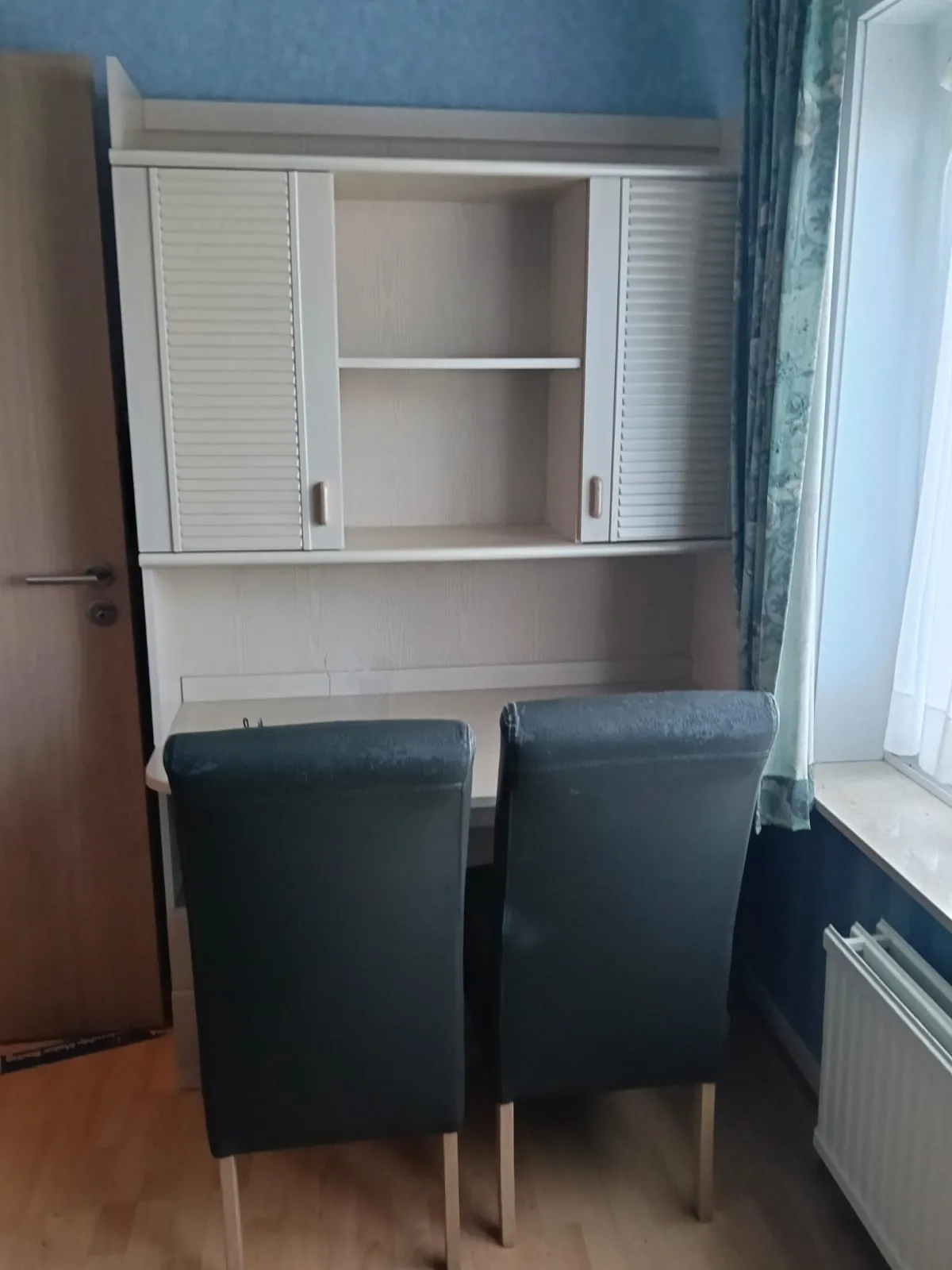 Witte bureaukast met rolluik en twee zwarte stoelen