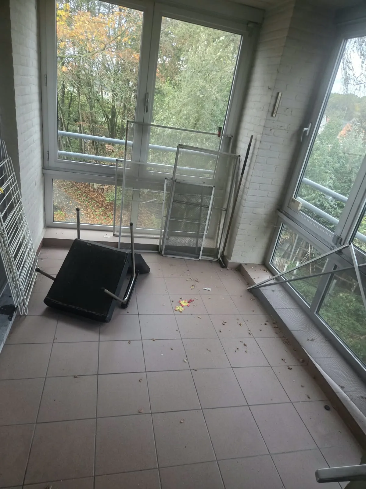 Lichte kamer met grote ramen en een omgevallen stoel op de tegelvloer