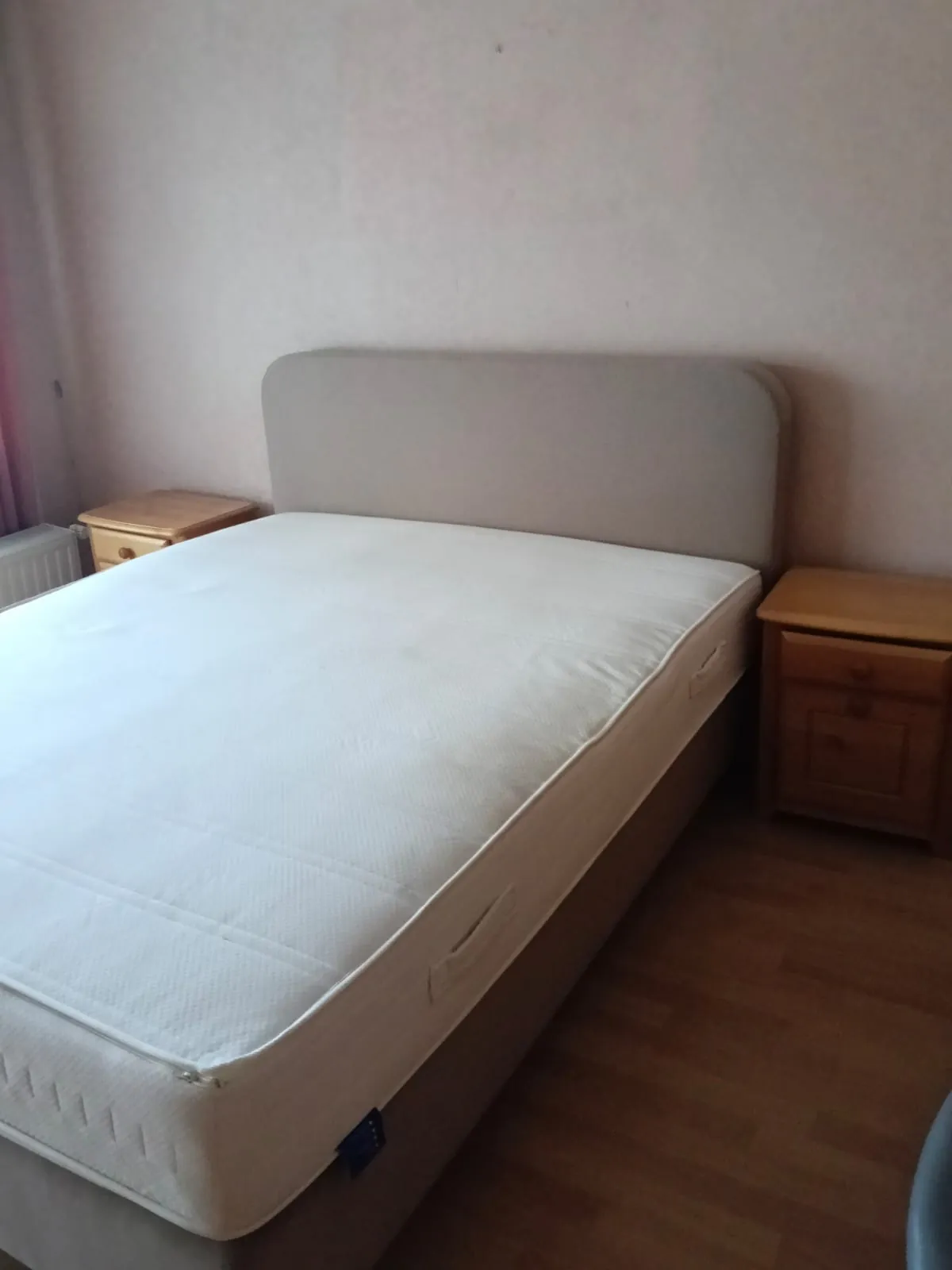 Tweepersoonsbed met matras en twee houten nachtkastjes