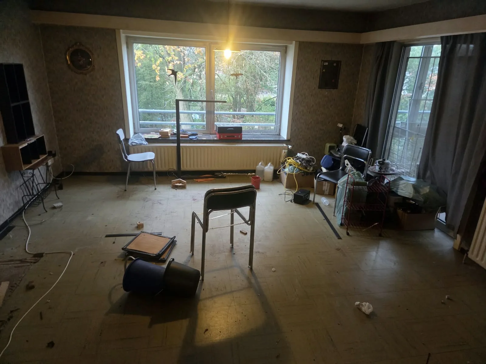 Woonkamer met achtergebleven spullen, stoelen en dozen